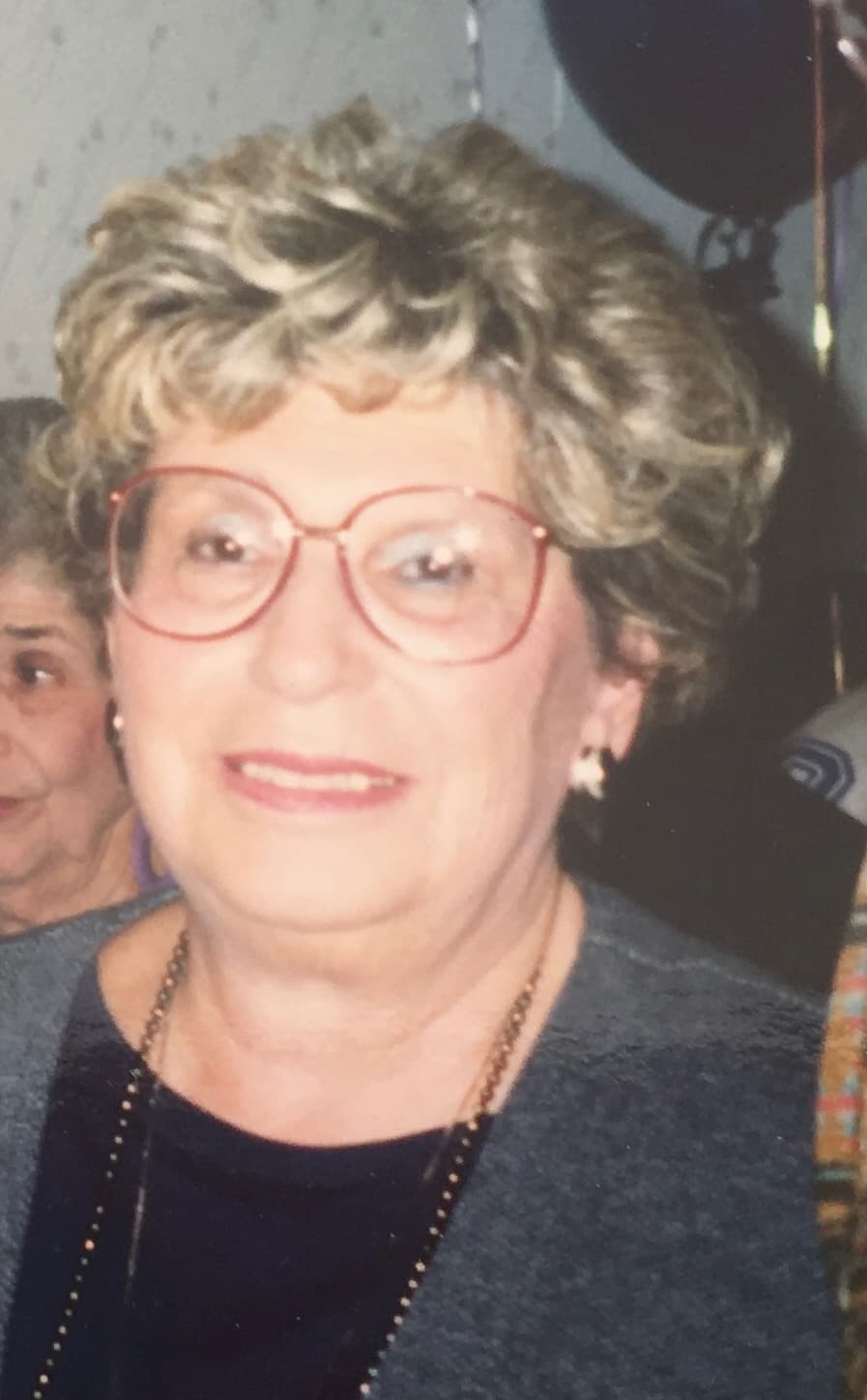 A real photo of a grandmother with red glasses and curly blonde hair — the kind of photo you might upload to start your book